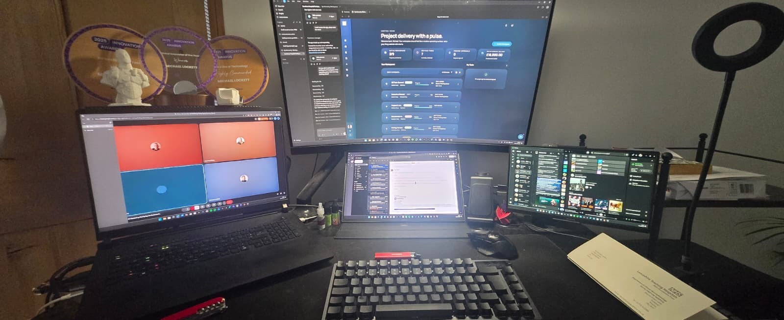 Michael Lockett's working desk with multiple screens, awards, dashboard interfaces, and development tools.